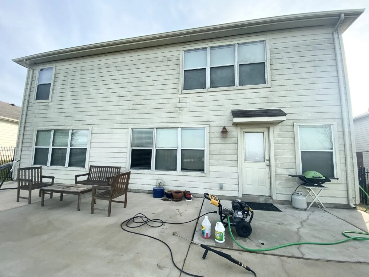 Mildew-stained siding and patio before pressure washing